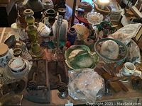 Full table view showing assorted decor including vintage irons, candlesticks, ceramics, and glassware