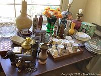 Wide view of tabletop showing lamps, glassware, ceramics, figurines and decor