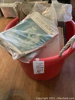 Large red plastic bin filled with various old vintage magazines and brochures in plastic bags.