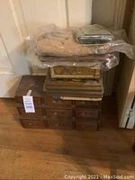 Overall view of the vintage wooden hardware drawers showing multiple small drawers stacked with vintage boxes and decor on top.