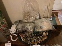 Photo showing large assortment of costume jewelry beads and pieces in plastic bags and laid out on a round tray