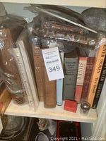 Shelf of vintage books on silver collecting with visible wear and protective covers, including a tag marked 349