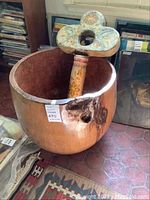 Large wooden pot with large paper mache key decoration placed inside. Damage visible on pot rim and key handle.