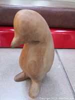 Photo of carved wooden penguin sculpture with smooth surface and detailed beak and feet.