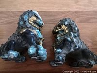 Oblique view of patinated metal guardian lion pair on wooden surface