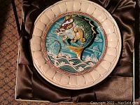 Top view of the ceramic plate showing detailed 3D fish and dragon gate design with cream border.