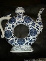 Front and side view of porcelain tea pot with circle shaped body and blue floral decorations