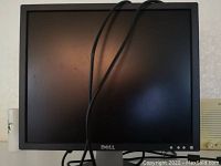 Front view of Dell 19-inch monitor showing the screen, Dell logo below screen, and control buttons at the bottom right. Power cable draped over screen.