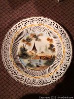 Porcelain plate with pierced lattice rim, village church, bridge and ducks scene in natural colors with gold trim