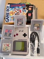 Game Boy console, five Game Boy cartridges in clear cases and cable arranged in packaging tray