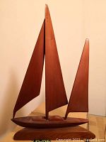 Wooden sailboat sculpture with smooth, minimalist wooden sails and polished base.