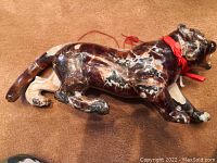 Side view of dark marbled stone tiger sculpture with red ribbon