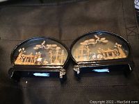 Pair of miniature semi-circular wood carvings with detailed scenic elements and Buddha figures, shown from above on a surface