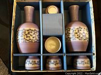 Top view of boxed sake set showing two bottles, four cups, and cloth insert in original box.