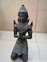 Front view of the resin statue showing detailed ornamentation and kneeling posture.