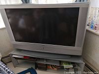 Front view of Sony Wega 50 inch TV sitting on the glass shelf with storage underneath.