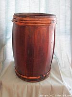 Full front view of the wooden barrel standing on cloth with light blue curtain background.