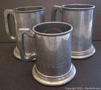 Three vintage pewter mugs with solid handles and glass bottoms, arranged grouped together.