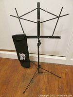Fully assembled On-Stage folding music stand with arms extended, and storage bag beside it.