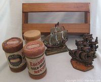 Overall view of three Edison wax cylinder records in original cylindrical boxes, three nautical-themed bookends, and an oak shelf against white background.