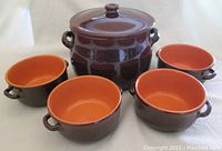 Full set of the covered crock and four matching bowls arranged in front with crock center back and bowls surrounding it.