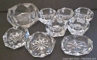 Group of 9 vintage/antique non-footed glass salt cellars arranged on a surface showing various shapes and starburst base patterns