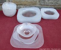 Full set of dinnerware pieces grouped by type: bowls stacked, salad plates stacked, dinner plates stacked, all square-shaped with clear smooth tops and textured frosted bottoms.