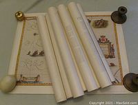 Rolled and flat vintage maps displayed showing paper texture and edges with wooden weights holding flat one open.