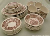 Overall view of stacked dinnerware pieces showing multiple plates, bowls, cups and saucers with copper engraving designs depicting historical Chinese export scenes.