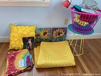 Yellow sunflower and flower pillows, two sunflower paintings, dog photo frame, vintage yellow bedspread, and folded tie dye valances on floor