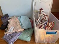 Overview image showing folded sweaters, silky pajamas with tags, weatherproof boots, and storage bins filled with hangers