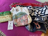 Lot of vintage Celtics t-shirt, Red Sox blanket, Murphy's Law tea towel on purple surface