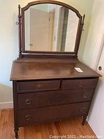 Full front view of the solid wood vintage dresser with attached arched mirror showing four drawers and decorative drawer pulls.