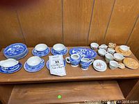 Photo showing full lot of childrens dish sets including blue willow pattern, peach luster, and Madeline character pieces arranged together