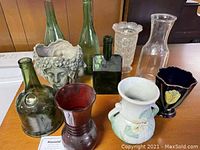 Photo of assorted vases including Weller pansy vase, face planter, and various glass bottles and vases showing overall lot