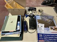 Overview of lot with office supplies and books packed in open box and on table