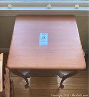 Top view of the square light cherry stained wooden parlor table showing surface with minor scuffs and dings.