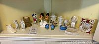 Shelf of assorted small ceramic and stone knickknacks showing overall lot contents including chickens salt and pepper shakers, various figurines, and small ashtrays
