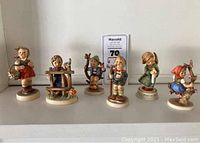 Six Hummel figurines in a row showcasing different characters and poses.