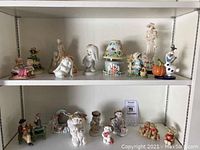 Shelf display with assorted china and resin figurines including animals, angels and seasonal characters.