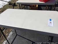 Top view of the white plastic tabletop, showing its rectangular shape and some surface scratches.