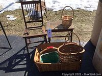 Wooden cane top side table, wooden chair, and assorted baskets outside on asphalt with some snow visible in the background