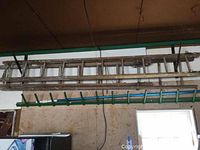 Three wooden ladders hanging on wall, showing general size and condition with paint marks and wear.