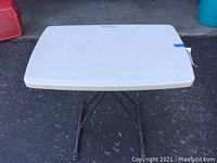 Top view of the rectangular white plastic tabletop showing scratches and wear marks.