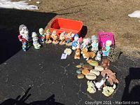 Wide view showing entire assortment including Disney dwarfs, Precious Moments figures, dogs, bunnies, inspirational stones, red and pink plastic crates