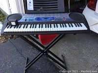 Full view of Casio LK-40 keyboard on X-stand with power cable plugged in
