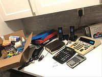 Full view of the office items including Panasonic cordless phones, binders, calculators, stationery box, and blank CDs