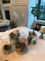 Photo of clear glass vases and decorative balls, elephant figurines, brass bell, and candle holders on table