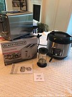 Black+Decker toaster on box, Hamilton Beach rice cooker, and coffee press displayed on table near window with fireplace in background