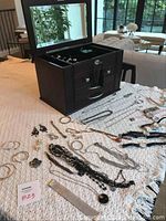 Wooden jewelry chest open on table with mirror visible and jewelry pieces arranged around it